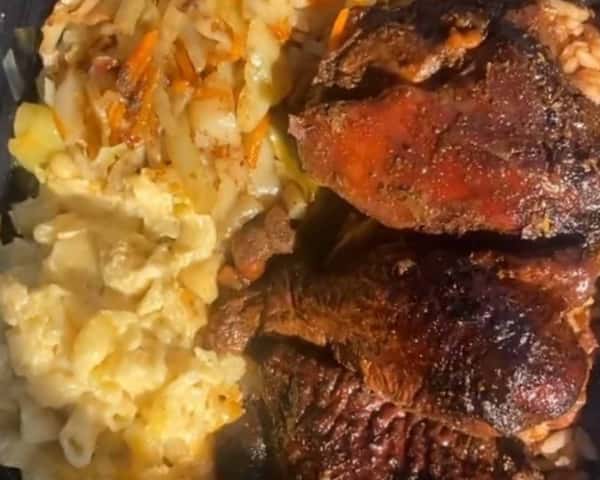 Jamaican jerk chicken served with creamy macaroni and cheese, steamed cabbage, and rice and peas.