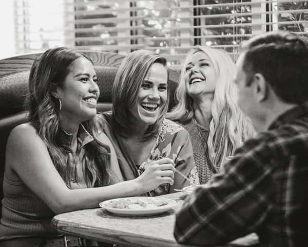 A group of men and women smile and laugh while sharing a dinner at Chuck A Rama