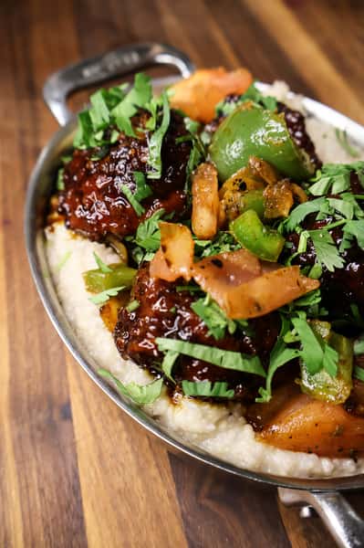 Barbecue-glazed meatballs served over creamy grits with sautéed bell peppers and fresh chopped cilantro.