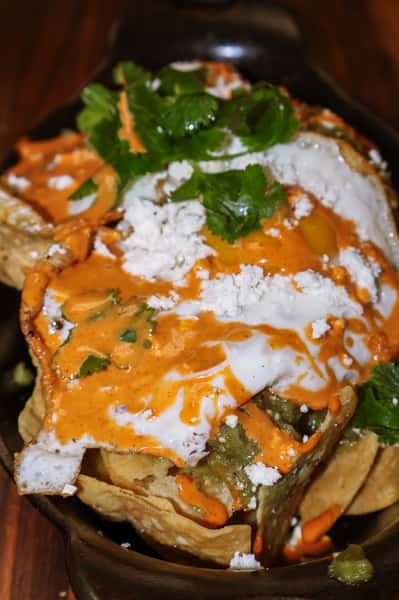 Chilaquiles topped with fried eggs, queso fresco, fresh cilantro, and drizzled with a creamy red sauce and green salsa.