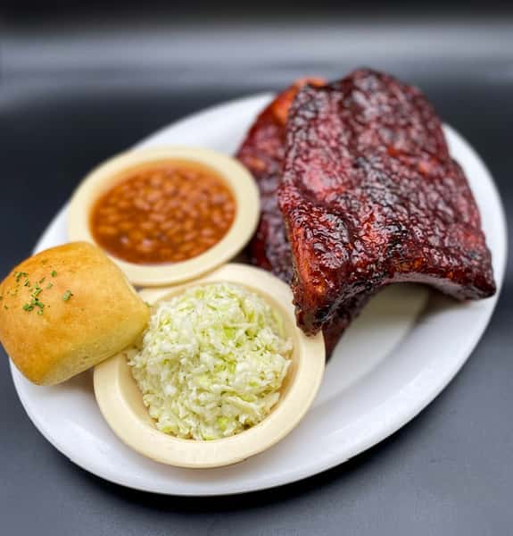 Plate of BBQ ribs with baked beans, coleslaw, and a dinner roll.