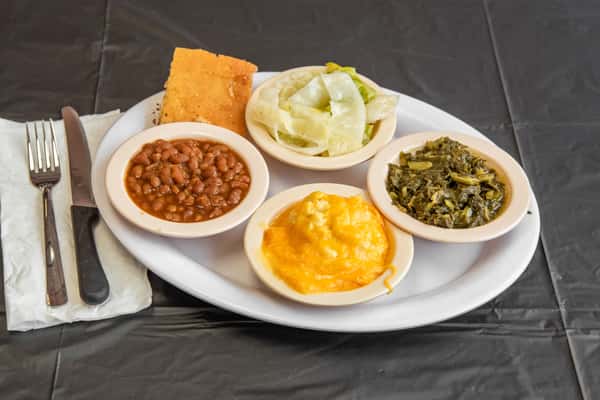 Baked beans, mac and cheese, collards, cornbread and cabbage on a plate