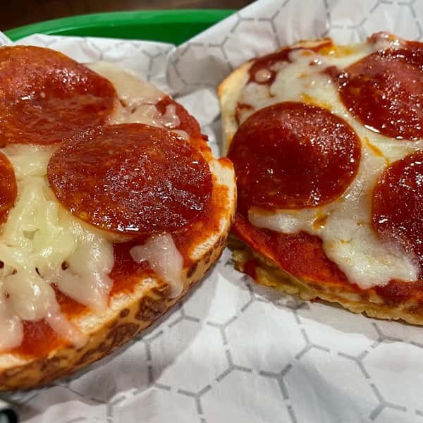 Two mini pepperoni pizzas with melted mozzarella and zesty tomato sauce, served in a green basket on wax paper at Liberty Brew.