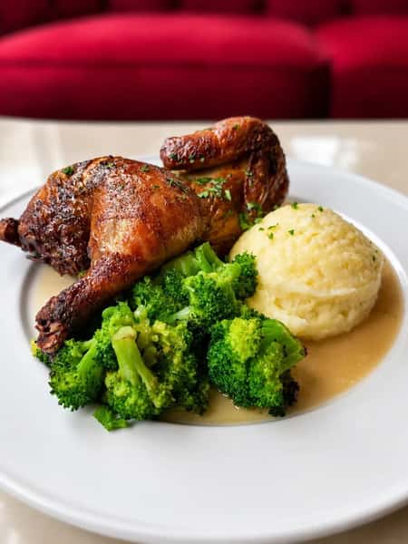 Backed half chicken on a plate served with mashed potatoes and broccoli