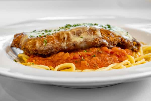 Classic chicken Parmesan served over spaghetti with marinara sauce, topped with melted mozzarella and garnished with fresh parsley on a white plate