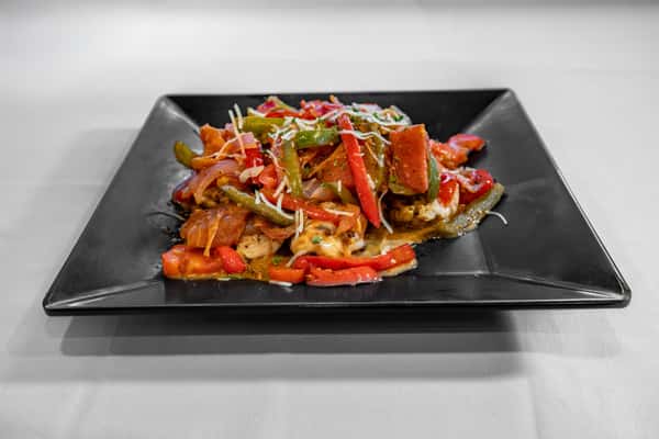 Grilled chicken breast topped with a colorful medley of sautéed red and green bell peppers, onions, and shredded cheese, served on a sleek black square plate.