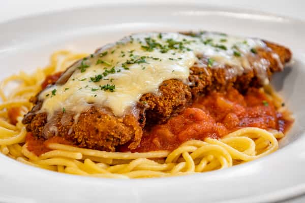 Close-up of crispy chicken Parmesan topped with melted cheese over spaghetti noodles and marinara sauce, garnished with chopped parsley.