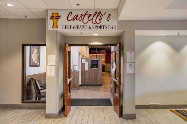Entrance to Castello's Restaurant & Sports Bar with double doors open under a branded sign featuring a Budweiser logo and inviting interior view.