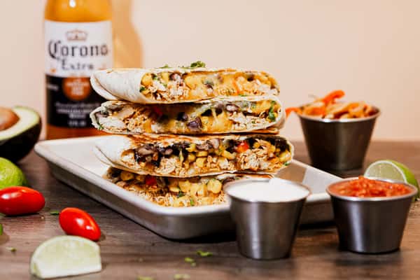 A stack of cheesy grilled chicken quesadilla wedges served with fresh salsa, sour cream, and jalapeños