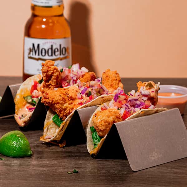 Three soft corn tacos with fried chicken, topped with fresh pico de gallo