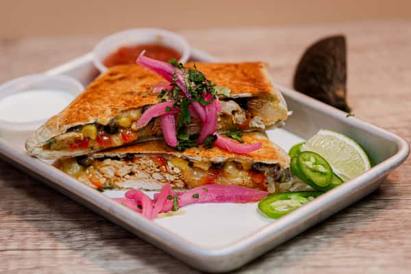 An overhead shot of sliced, golden-brown quesadillas filled with melted cheese and seasoned meat