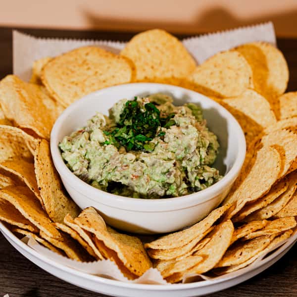 Bowl of vibrant green guacamole and toasted tortilla chips