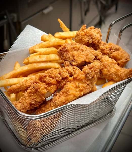 Classic fried chicken tenders paired with golden French fries, served in a metal basket lined with white parchment paper.