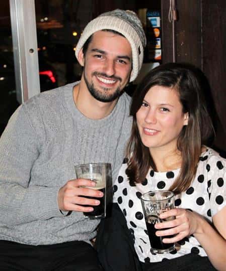 Male and female in picture, both are smiling and holding glasses of beer
