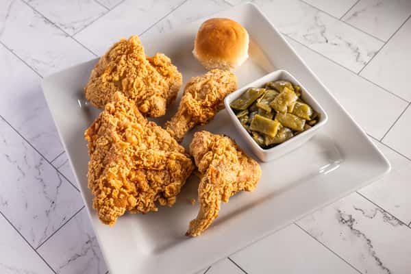 Southern fried chicken plate with crispy chicken pieces, green beans, and a soft dinner roll