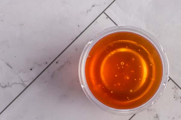 small cup of sweet chili dipping sauce with glossy amber color, served as a classic condiment for appetizers