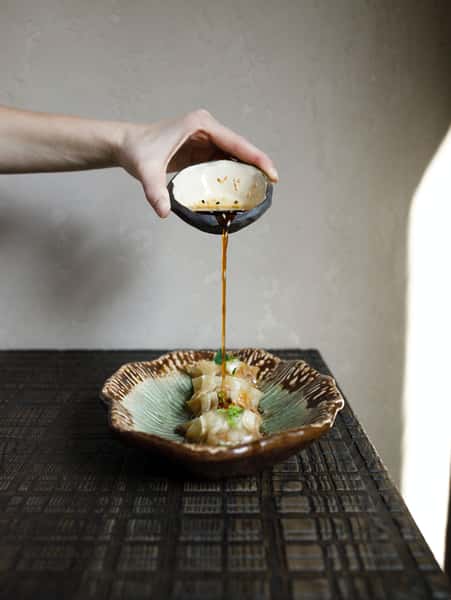 Soy sauce being poured on dumplings
