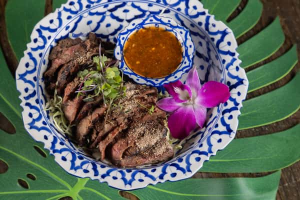Grilled sliced steak served with rich Thai dipping sauce and aromatic seasonings, delivering bold flavor and perfectly tender texture.
