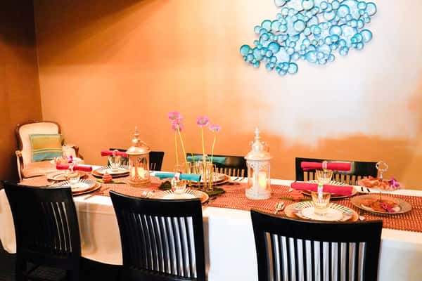 elegantly set Thai restaurant dining table with decorative lantern centerpieces, floral accents, and warm ambient lighting for intimate dining experience