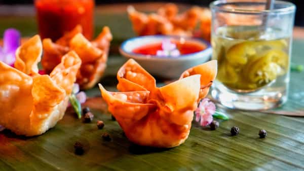 Crispy fried wonton cups served on banana leaf with sweet chili sauce and pickled vegetables garnish