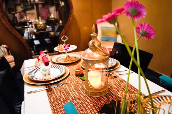 elegant Thai restaurant table setting with decorative lantern candle, floral accents, and neatly arranged plates creating an intimate dining atmosphere