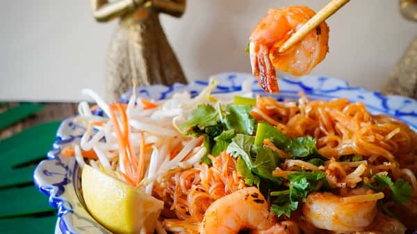 Pad Thai with shrimp, rice noodles, bean sprouts, cilantro, and lime wedge served in a decorative bowl
