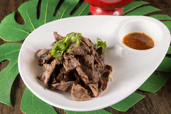 Grilled Thai-style beef served tender and flavorful with fresh herbs and a rich house dipping sauce, delivering bold savory taste in every bite.