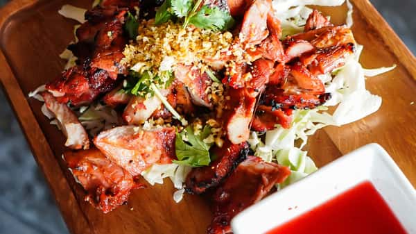 Thai grilled chicken (gai yang) sliced over cabbage with garlic topping and sweet chili dipping sauce