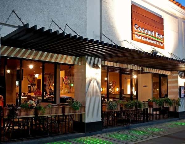 exterior of Coconut Bay Thai restaurant with outdoor patio seating, warm interior lighting, and inviting evening dining atmosphere