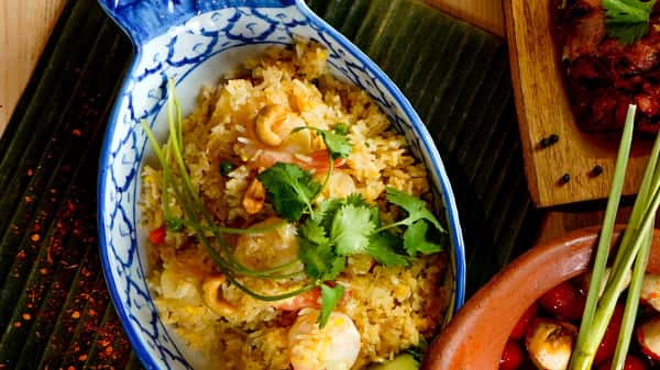 Thai pineapple fried rice with shrimp, cashews, and fresh cilantro served in a decorative ceramic dish