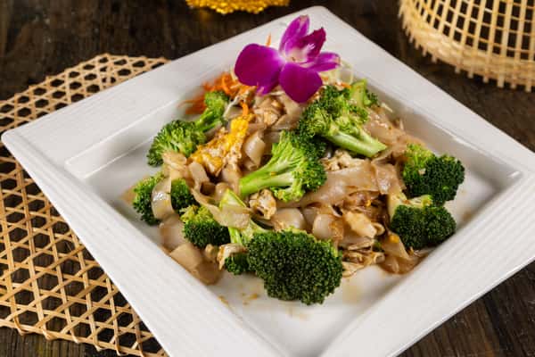 Savory Thai stir-fried noodles tossed with fresh vegetables and flavorful sauce, served alongside crispy spring rolls for a satisfying and authentic Thai dining experience.