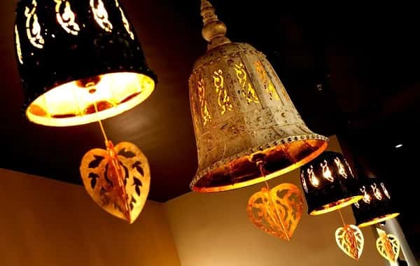 warm ambient restaurant lighting with decorative hanging lanterns and intricate Thai-style metal lamps creating a cozy dining atmosphere