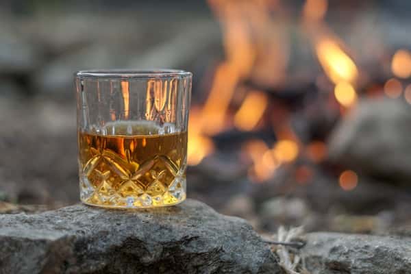 Whiskey glass by an outdoor firepit at Sivas Tavern with cozy lounge and nightlife vibes