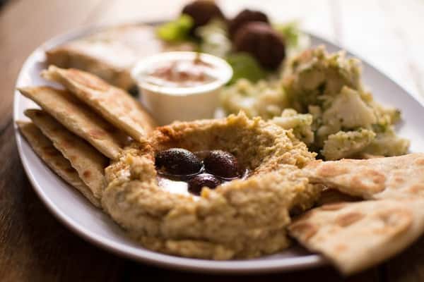 Mediterranean hummus platter with olives and pita bread at Sivas Tavern featuring fresh appetizer options