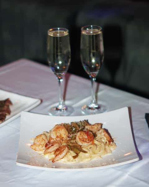 Elegant pasta dinner with champagne glasses at Sivas Tavern featuring upscale dining and romantic restaurant ambiance