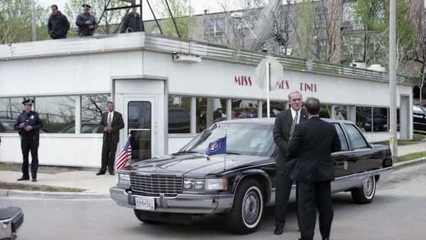 outside of diner surrounded by a limo and men in suits