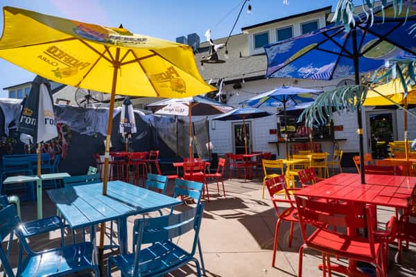 Colorful outdoor patio with red, blue, and yellow tables and branded umbrellas creating a lively dining atmosphere.