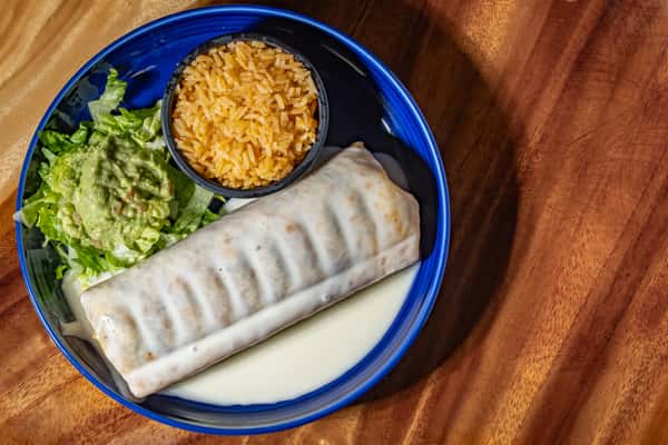 A flavorful Mexican entrée featuring a burrito generously topped with creamy white queso sauce, served alongside fluffy Mexican rice, crisp lettuce, and a scoop of guacamole on a blue plate.
