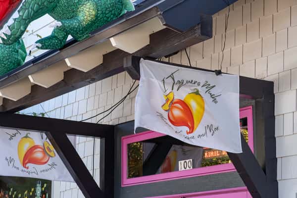 White flag outside displaying the "I Taquero Mucho Mexican Cuisine and Bar" logo with chili peppers and a sombrero.