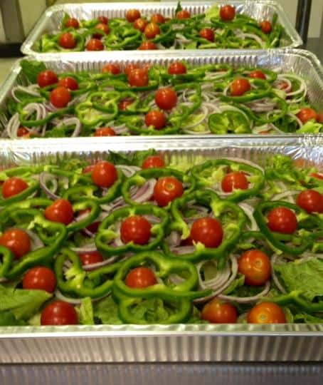 House salad in to-go containers with cherry tomatoes, green peppers, and red onion