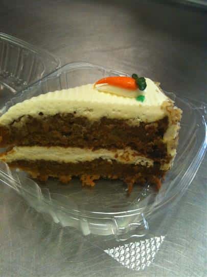 a slice of carrot cake topped with a mini carrot made of icing
