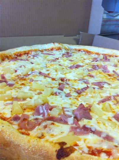 Hawaiian pizza topped with tomato sauce, mozzarella cheese, ham, and pineapples