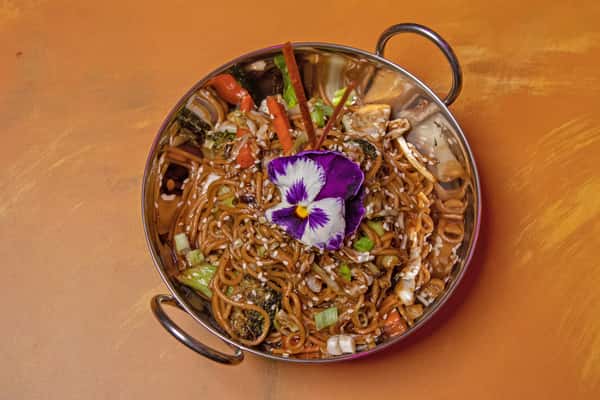 Bowl of Chinese noodles garnished with an edible flower
