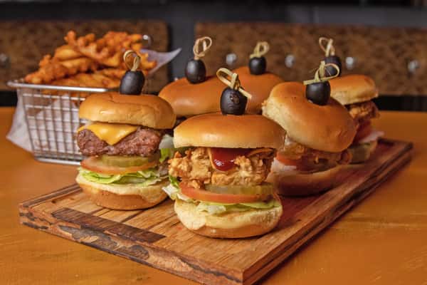 Chicken and beef sliders stacked on a wooden serving board