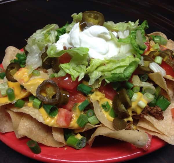 loaded chips topped with meat, lettuce, tomatoes and sour cream