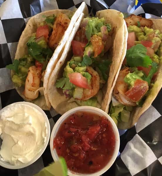 three shrimp tacos with lettuce and dipping sauces