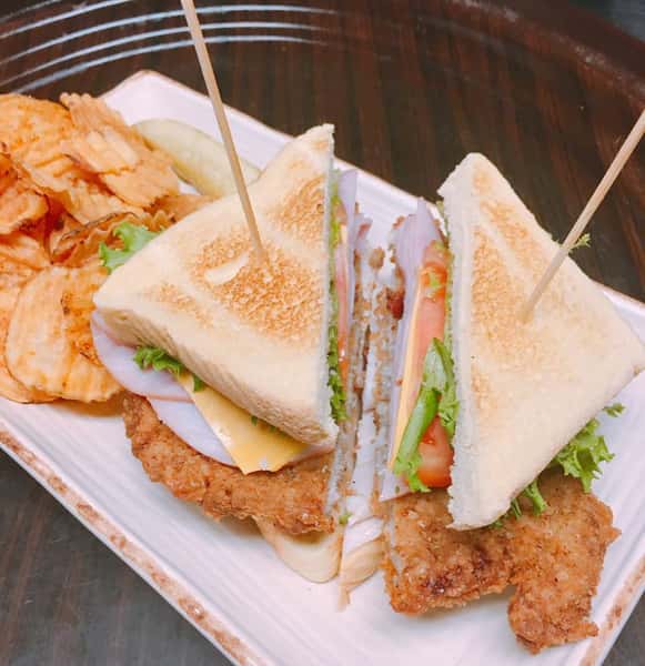 turkey club sandwich with fried chicken and a side of chips
