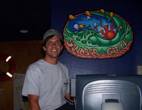 an emplyee posing with the Sandbar and Grille logo