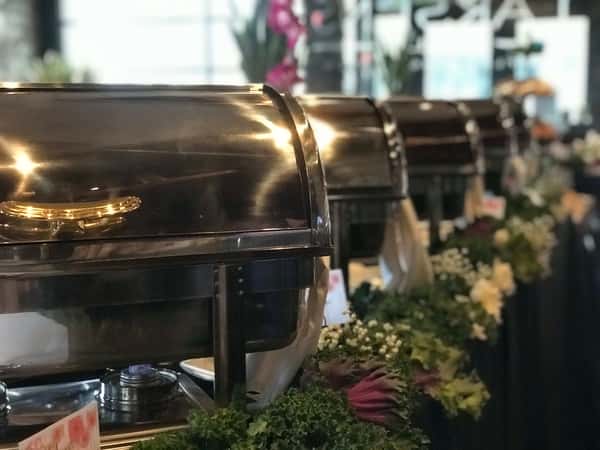 Stainless steel chafing dishes on a buffet table.