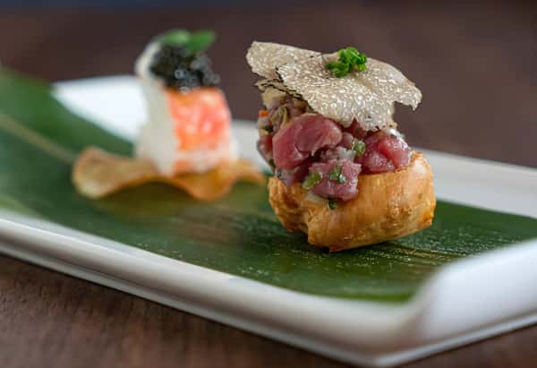 Plated beef tartare topped with a crisp garnish and microgreens on a white dish.